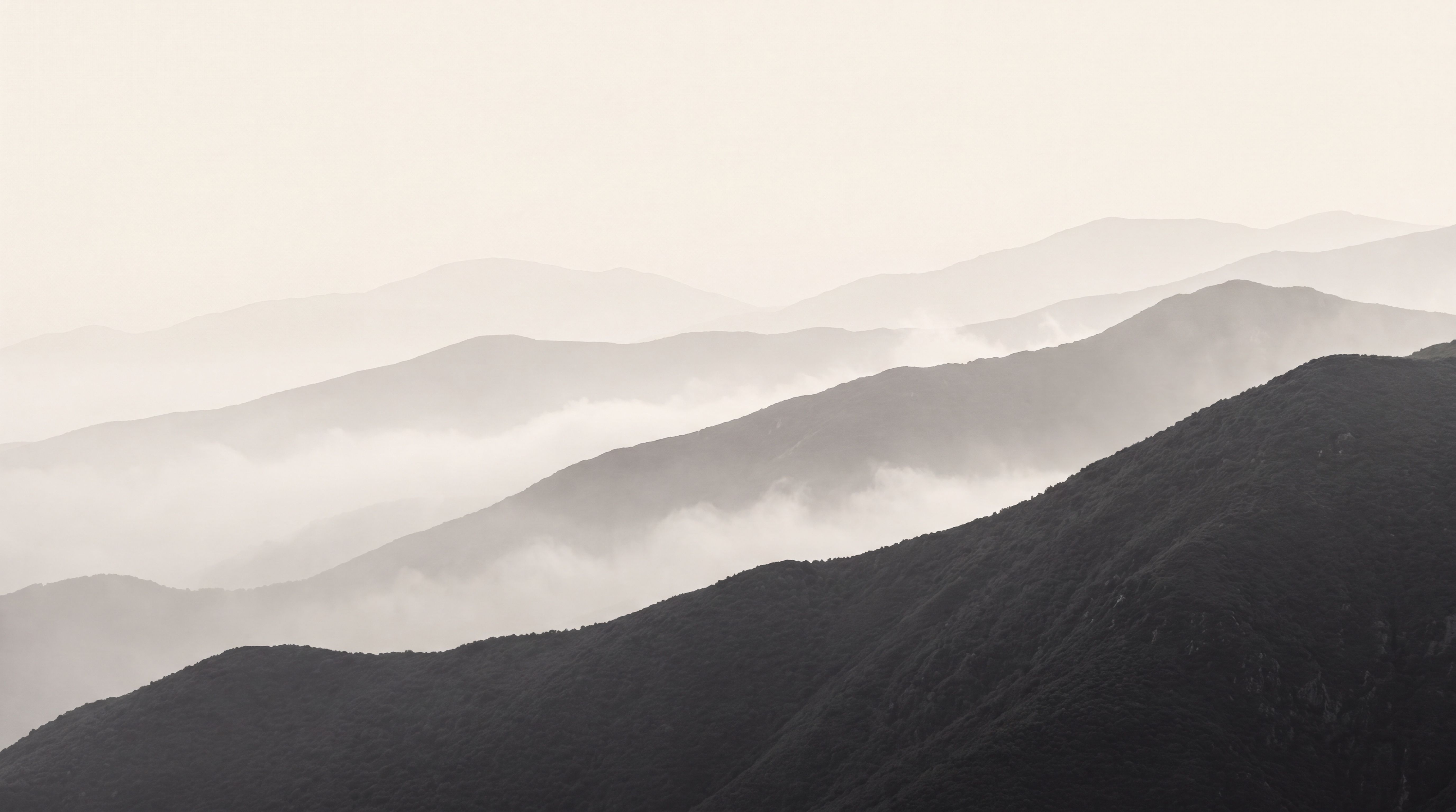 Layered mountain ridges receding through pale mist